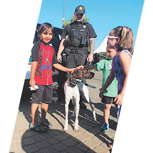 Officer with K9 interacting with young children header sliding image.