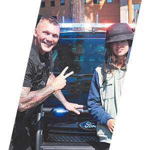 Officer with patrol car interacting with young child header sliding image.