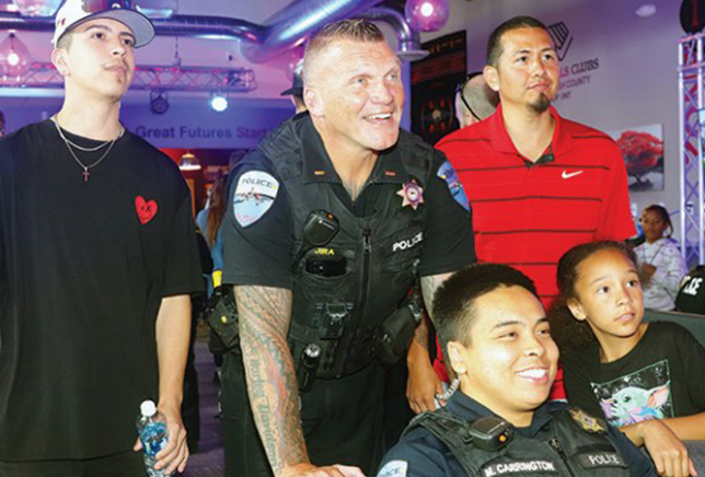 Officers in a large room at the Tulalip Boys and Girls Club, interacting with children and young adults for career day. 