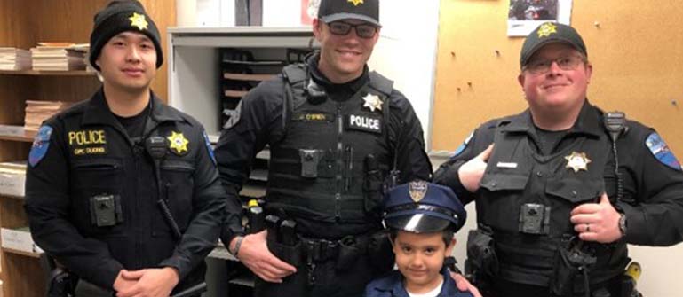 Three officers of Tulalip Tribal Police with young child in uniform, experience chief for a day tablet image.